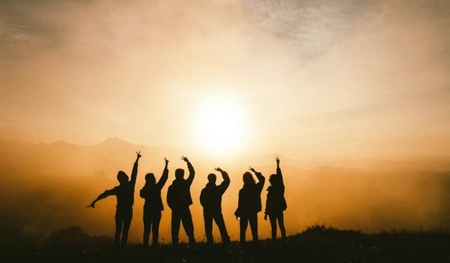 Silhouette of six people posing against a sunset