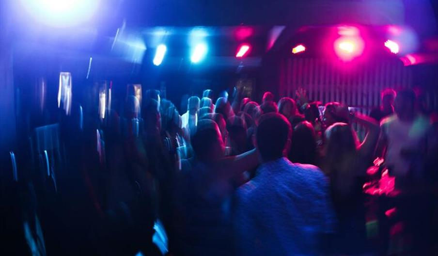 Vibrant nightclub scene with blurred dancing crowd and colorful lights