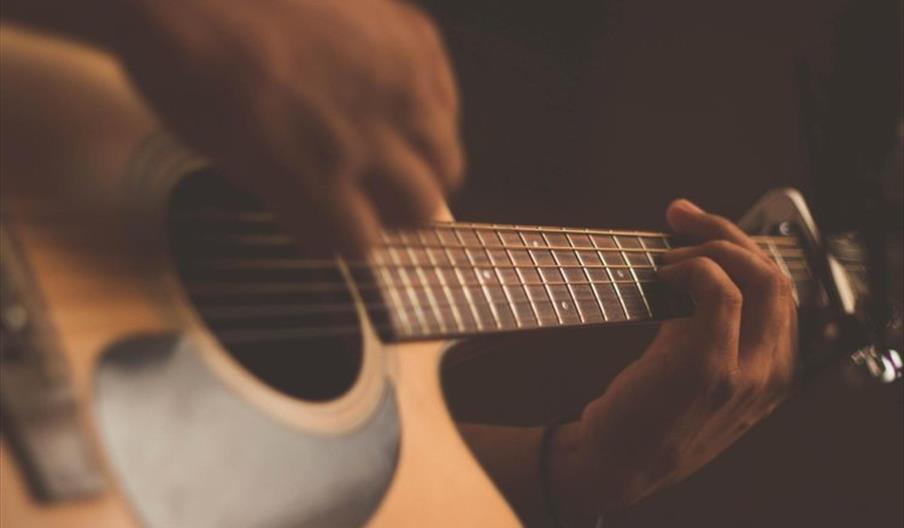 Person playing acoustic guitar with a capo