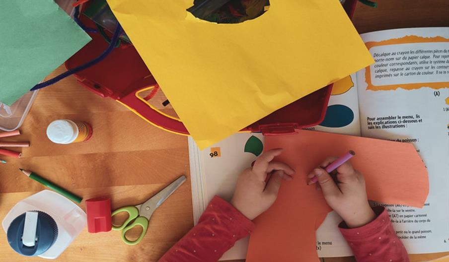 A child surrounded by bright cardboard at a craft table