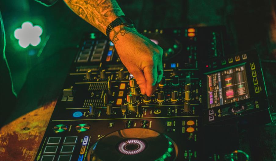 Electric mixing decks being operated by person with tattoos