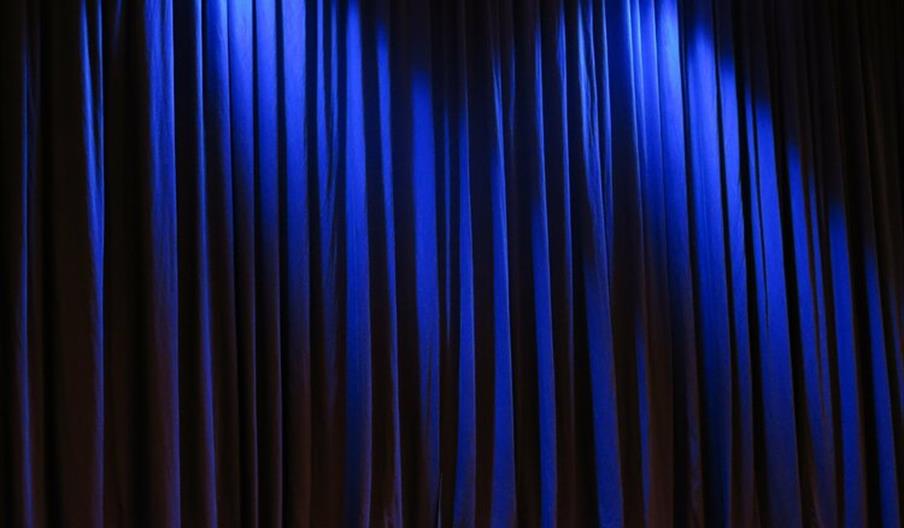 Dark blue stage curtain with light shining from spotlights above