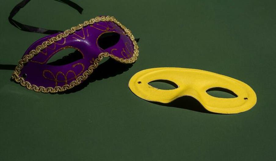 Purple and yellow masquerade masks on green background