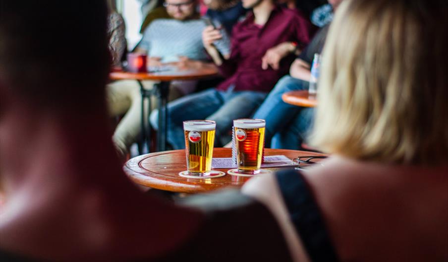 Two pints of beer on a table in a group of people
