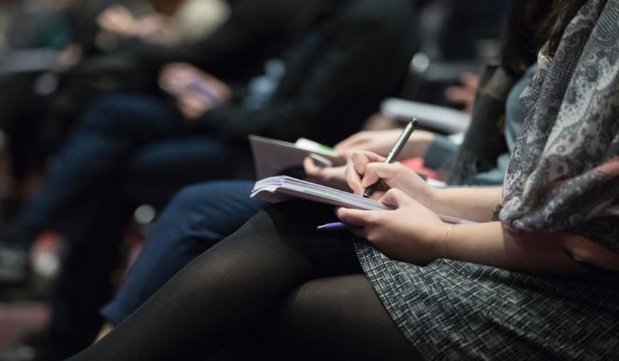 People taking notes at a lecture